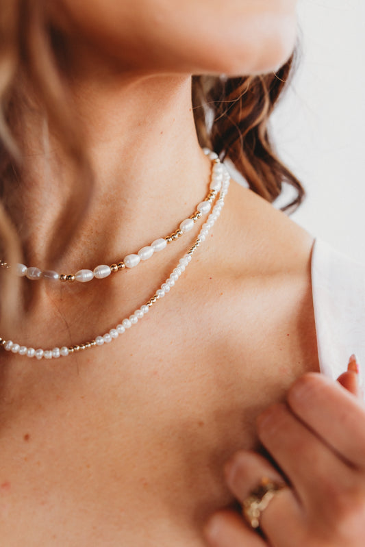 Close-up of a person wearing a pearl necklace with a blurred background