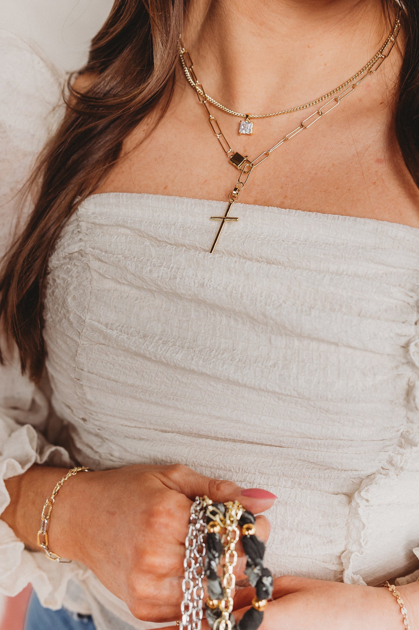 Close-up of a person wearing multiple gold necklaces and bracelets.