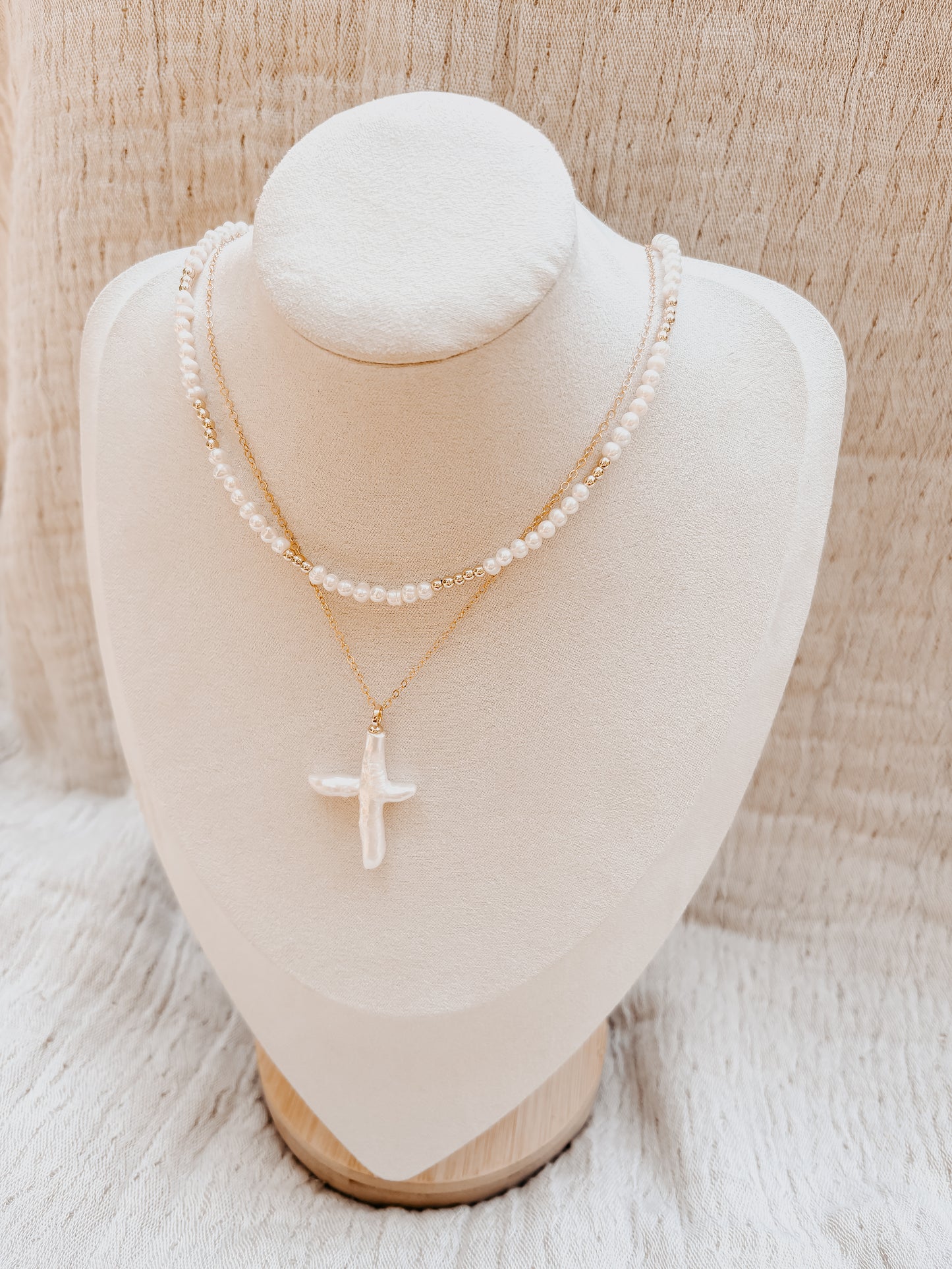 Two necklaces on a mannequin bust against a neutral background
