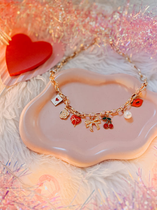 Necklace with charms on a cloud-shaped dish with a red heart and glittery background