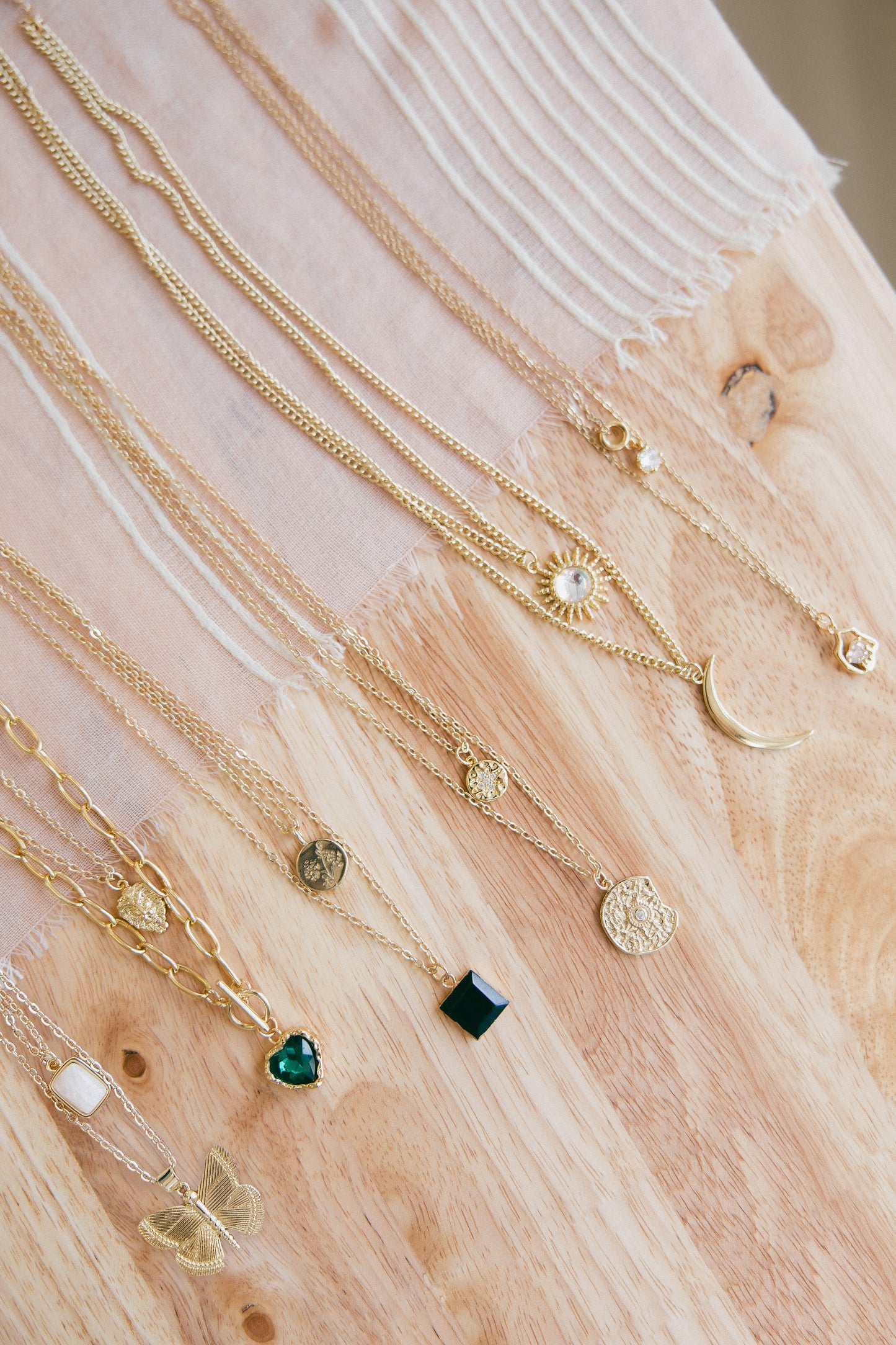 Gold necklaces with various pendants on a wooden surface