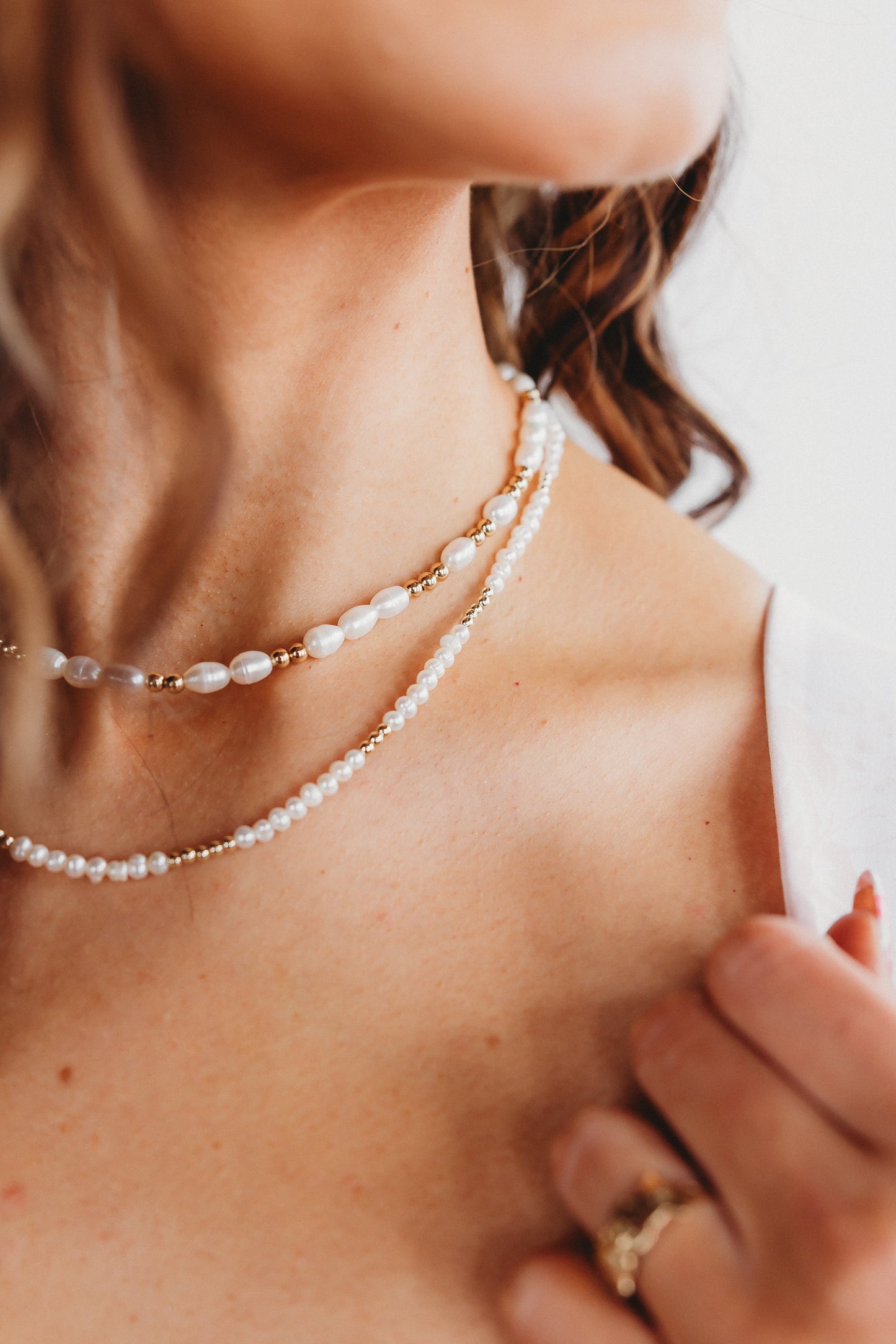 Close-up of a person wearing a pearl necklace with a blurred background