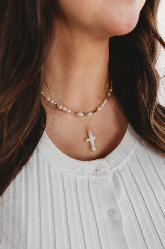 Layered Necklace with a pearls and a pearl cross pendant worn by a person