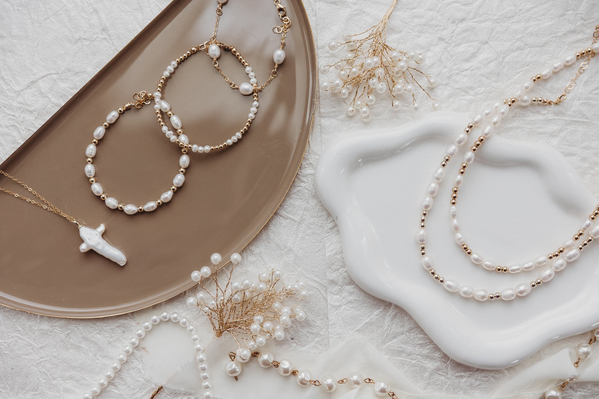 Pearl necklaces and bracelets on a textured surface with decorative elements