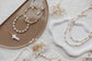 Pearl necklaces and bracelets on a textured surface with decorative elements