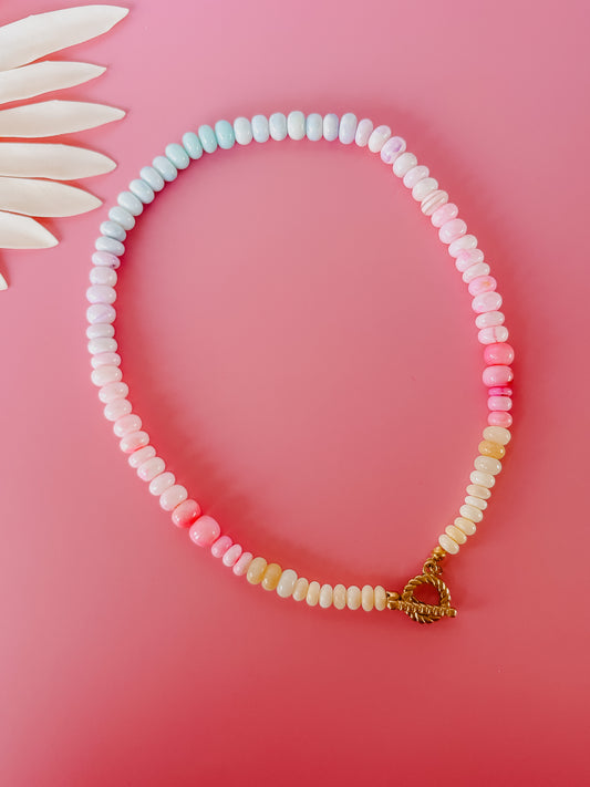 Pastel beaded necklace with a gold clasp on a pink background