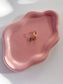 Gold hoop earrings on a pink ceramic dish with a white background