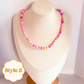 Pink gemstone necklace with colorful beads on a mannequin bust.